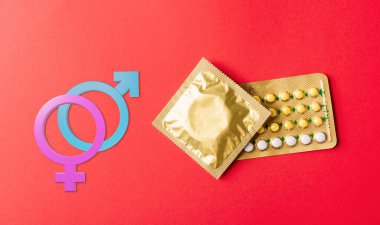 Dünya Cinsel Sağlık veya AIDS Günü. Erkek, kadın, prezervatif, doğum kontrol hapları, hormonal doğum kontrol hapları, kırmızı arka planda izole edilmiş stüdyo fotoğrafları.