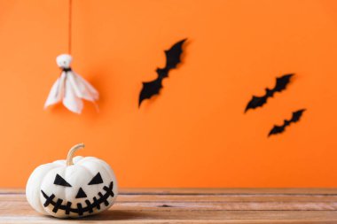 Komik Cadılar Bayramı dekorasyon partisi, şirin balkabağı hayaleti ürkütücü Jack o fener yüzü, siyah örümcek ve yarasalar ahşap masada, stüdyo çekimi turuncu arka planda, mutlu tatil konsepti