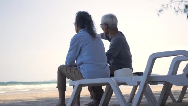 幸せなアジアの家族は 高齢者のカップルが一緒に話してビーチ旅行休暇に背を向けて椅子に座って ロマンチックな高齢者をお楽しみください旅行夏休み 計画生命保険退職カップルのコンセプト — ストック動画