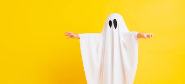 Komik cadılar bayramı çocuğu kavramı, yakın plan beyaz kostümlü küçük şirin çocuk cadılar bayramı hayaleti korkunç, sarı arka planda izole edilmiş stüdyo resmi.