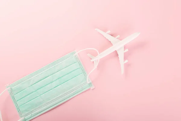World Tourism Day, Top view model plane and medical face mask, Holiday accessory beach trip travel vacation studio shot isolated pink background with copy space