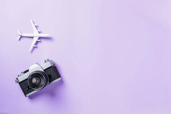 コピースペース ビジネス旅行 休暇の夏の旅行のコンセプトで紫色の背景に隔離されたレトロカメラフィルム 飛行機旅行アクセサリーのトップビューフラットレイアップ — ストック写真