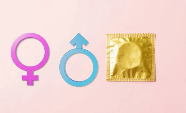 World sexual health or Aids day, Top view flat lay condom in wrapper pack and Male and female gender signs, studio shot isolated on a pink background, Safe sex and reproductive health concept