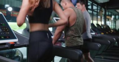 Spor sağlık yaşam tarzı konsepti olan fitness jimnastik kulübünde egzersiz yaparken makine koşu bantlarında koşan bir grup atletik genç.