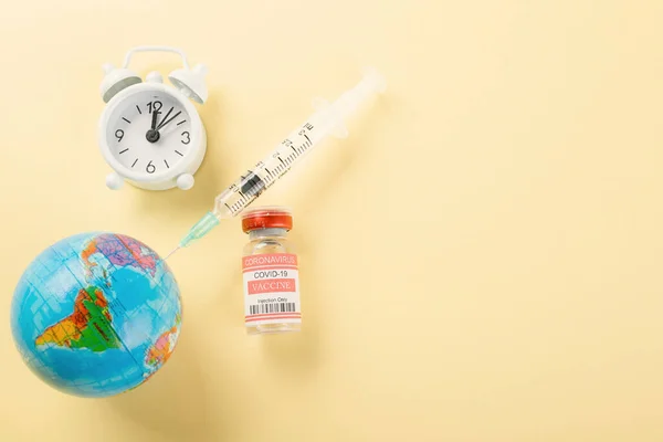 Vaccine vials bottles, syringes for vaccination against coronavirus and globe, medicine illness, COVID-19 disease vaccine isolated on yellow background