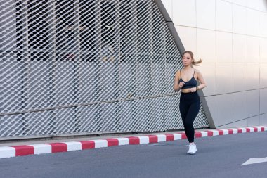 Egzersiz meraklısı kadın, modern kentsel caddelerde bina cephesine karşı sağlıklı aktif yaşam tarzını teşvik etmek amacıyla canlı şehir koşusu sırasında dışarıda spor yapıyor..