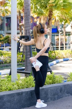 Formda bir kadın spor egzersizi yapıyor. Açık havada egzersiz yapıyor. İnsanlara ilham veriyor, canlı şehir parkı ortamında formda bir vücut sağlıyor..