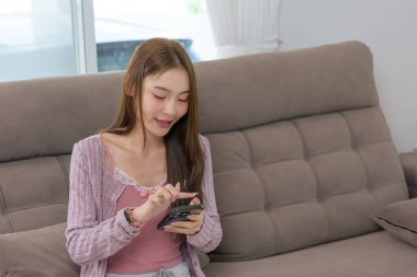 Genç kadın mutlu ev aktiviteleri, insanlar cep telefonu etkileşiminden, sosyal medyaya bakmaktan, arkadaşlarla sohbet etmekten, rahat koltukta keyif almaktan,.