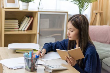 Ödev yapan, öğrenim gören, sınav için yazı yazan, görevine odaklanan, gelecekteki başarılara hazırlanan, kendini eğitime ve kişisel gelişime adamış bir genç kız..
