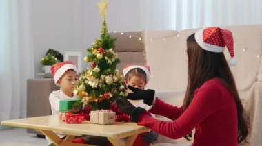 Mutlu bir aile Noel 'i evde kutluyor, ebeveynler ve iki çocuk minyatür ağacı altın ve kırmızı süslemelerle süslüyorlar, bayram kutuları düzenliyorlar, sıcak tatil atmosferinin tadını çıkarıyorlar..