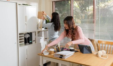 Genç iş adamları çalışmakla meşgul, finans ekibi modern ofiste danışmanlık yapıyor, belgeleri düzenliyor, biri teknolojiyi kullanıyor, diğeri ise raflardaki dosyaları düzenliyor, şirket amaçları için profesyonel takım çalışması..