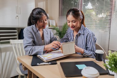 Çevrimiçi çalışan genç bayan iş arkadaşları ev idaresi takımını öğrenir proje tartışır, gelecek fikirleri planlar, modern masadaki önemli belgeleri kahve eşliğinde gözden geçirirler..