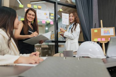 İş kadınları tanışıyor, proje üzerinde çalışan takım üyeleri meşgul, modern konferans salonunda toplantı yapıyorlar, başarılı strateji fikirlerini paylaşıyorlar, işbirliği ortamı sergiliyorlar..