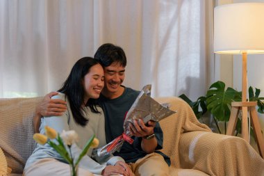 Mutlu genç çift, birbirine aşık erkek ve kadın, romantik sevgililer gününü evde kutluyorlar, tatlı anı ve çiçekleri paylaşıyorlar, birbirlerine sevgi gösteriyorlar..