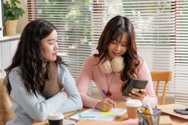 Genç iş adamları ofiste buluşur, finansal işlere danışırlar, hesaplama yapmakla, iş stratejilerini tartışmakla meşgul olurlar, gülümseyen genç kadınlar proje planlamada işbirliği yaparlar.