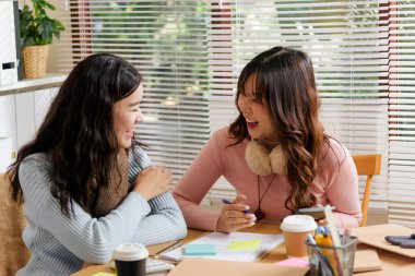 Meşgul genç iş kadınları ofiste buluşur, takım olarak çalışırlar, finansal projeye danışırlar, fikirleri paylaşırlar ve dokümanlarla verimli iş ortamının tadını çıkarırlar, kahve içerler..