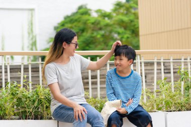 Anne, çocuk, yaz kenti aile kadını anne baba oğul açık havada kaynaşmayı seviyor, sıcak şehir manzarası, güçlü bir bağlantı yetişkin ve genci gösteriyor, canlı şehir arkaplanı, huzurlu yaz günü.