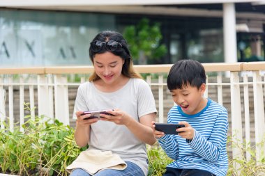 Anne, çocuk, yaz şehri sahnesi, aile kadın ve oğlu dışarıda gezici oyunlar oynamayı seviyor, ebeveyn ve çocuk şehir sokaklarında teknolojiyle bağlantı kuruyor, insanlar eğleniyor..