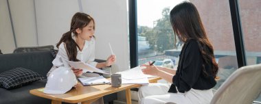 Kadınlar ofis işleriyle tanışıyor danışmanlık yapıyorlar, iş adamları önemli proje belgelerini tartışıyor, planlar gözden geçiriliyor ve şirket toplantısı sırasında yeni fikirler üretiliyor, masa başında beyaz inşaat başlığı takılıyor..