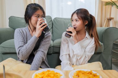 İki genç kadın lezzetli atıştırmalıklar yemekten, rahat oturma odasında ferahlatıcı içecekler içmekten, insanların kaliteli zaman geçirmesinden, kızların evde dinlenmesinden, mutlu anların paylaşılmasından, boş aktivitelerin paylaşılmasından hoşlanırlar..