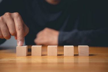 Yeni bir iş planı ya da yaratıcı bir fikir başlatmak için kavramsal bir işaret olan ilk tahta küpü işaret ederek bir adamın el hareketi yapması ve işaret etmesi..