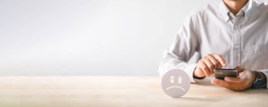 Müşteri olumsuz geri bildirim sunar, mutsuz kötü deneyim ifade eder, cep telefonuyla düşük tatmin oranı verir, üzgün yüz simgesi kötü hizmet değerlendirmesi gösterir.