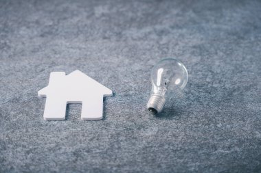 Ampullü beyaz ev emlak emlak enerjisini temsil ediyor. İpotek komisyoncusu aile bilgisi ampulü ve akıllı konut verimliliği için elektrik tasarrufu kavramı..