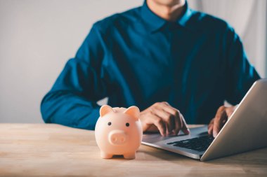 Araba, banka, öğrenim, e, eğitim, finans, çevrimiçi, para, elearning, internet hedefleri için tasarruf yapan adam ahşap ofis masasında oturan domuz bankası ile dizüstü bilgisayar kullanıyor.