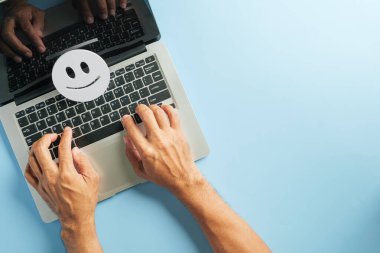 Müşteri geribildirimi ve müşteri memnuniyeti için dizüstü bilgisayar, klavyede yazı yazan eller, mutlu yüz simgesi pozitif anket sonuçlarını gösterir.