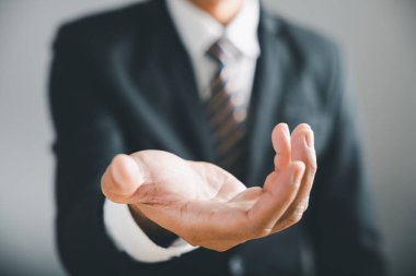 Arka planda takım elbiseli bulanık iş adamıyla uzanmış bir elin yakın çekimi..