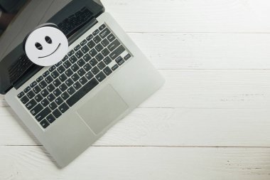 Müşteri değerlendirmesi ve memnuniyet anketi çevrimiçi dizüstü bilgisayar kullanılarak, olumlu geri bildirim gösteren gülen yüz emojisi, hafif ahşap arka planda bilgisayar ekranında iyi hizmet deneyimi gösterimi.