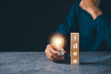 İş fikri büyümesi ampul çözeltisi, pazarlama el ele tutuşması ampul, kavram koyu dokulu taş ofis arka planında ahşap bloklar kullanarak yaratıcı fikirler getiriyor..