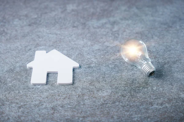 Beyaz Saray modeli ve parlayan ampul emlak enerjisini temsil ediyor, aile ipoteği emlak komisyoncusu bilgisi, elektrik enerjisinden tasarruf etmek için ampul konsepti.