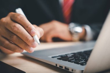 Dizüstü bilgisayar klavyesinin üzerinde beyaz bir kalem tutan elin yakın çekimi. Kaleme odaklanalım..