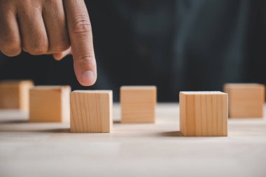 Bir el, bir sıra bloktaki ahşap bloğu işaret ediyor. Seçim, karar veya fırsat kavramı.