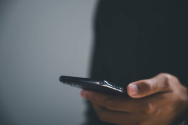 Arka planda bulanık bir akıllı telefonu tutan bir elin yakın çekimi..