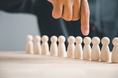 Parmaklar ahşap figürlerden birini işaret ediyor. En iyi adayı seçme kavramı.