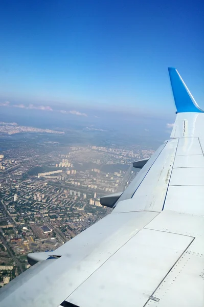 Ala de avião com uma cidade debaixo dela — Fotografia de Stock