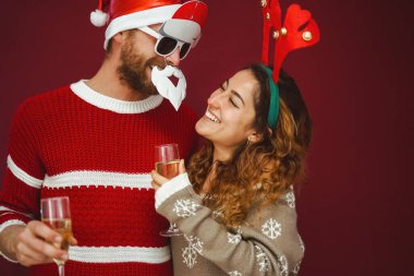 Mutlu çift Noel tatilini kutluyor, şampanya içiyor ve geleneksel Xmas aksesuarları takıyor.