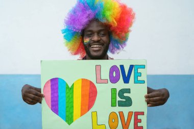 Mutlu Afrikalı adam gay onur festivali için bayrak tutarken eğleniyor.