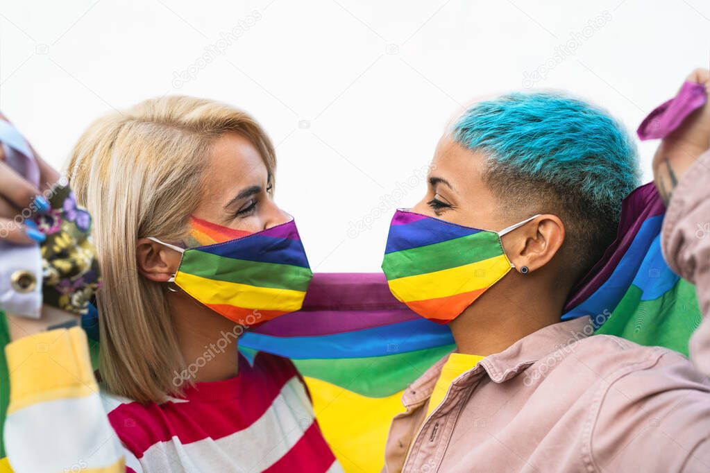 Happy gay couple wearing face mask celebrating gay pride event during corona virus pandemic