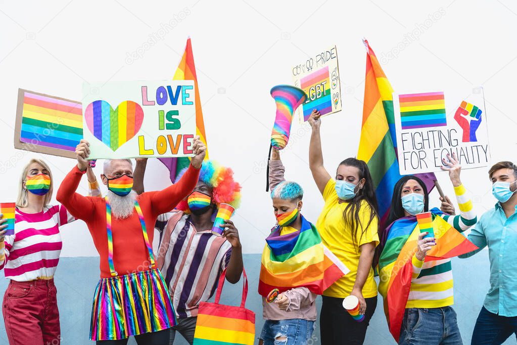 Happy Multiracial people wearing face mask celebrating at gay pride festival during corona virus - Group of friends with different age and race fighting for gender equality