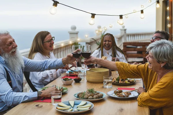 Mehrköpfige Senioren Freunde Haben Spaß Beim Gemeinsamen Essen Und Stoßen — Stockfoto