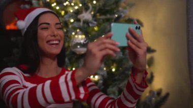 Mutlu genç kız, Noel tatilinde cep telefonu uygulaması kullanarak ailesiyle video görüşmesi yapıyor.