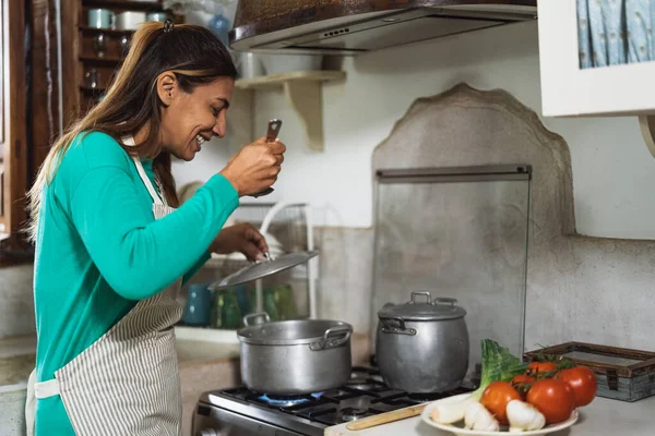 Latin mature woman cooking in old vintage kitchen - Smiling mother preparing lunch at home