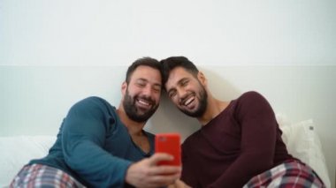 Yatakta cep telefonu kullanan mutlu eşcinsel çift - İlişki kavramında eşcinsel aşk ve cinsiyet eşitliği