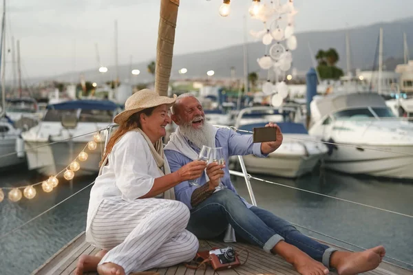 两对老夫妇在帆船度假的时候 一边自娱自乐一边敬酒 在乘船旅行时庆祝结婚周年的快乐成年人 爱情关系和旅行生活方式的概念 — 图库照片