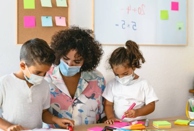 Corona virüsü salgını sırasında anaokulunda çocuk maskesi takan öğretmen - Sağlık ve Eğitim Konsepti