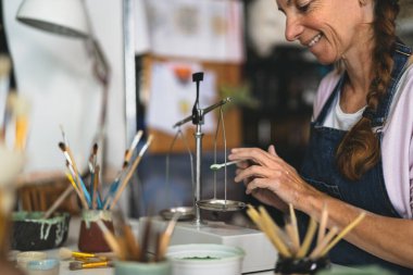 Çömlek atölyesinde boya tozu döken mutlu kadın.