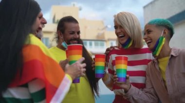 Farklı yaşlarda mutlu insanlar Corona virüsü salgını sırasında gay onur festivalinde tezahürat yapıyor ve kokteyl içiyorlar.